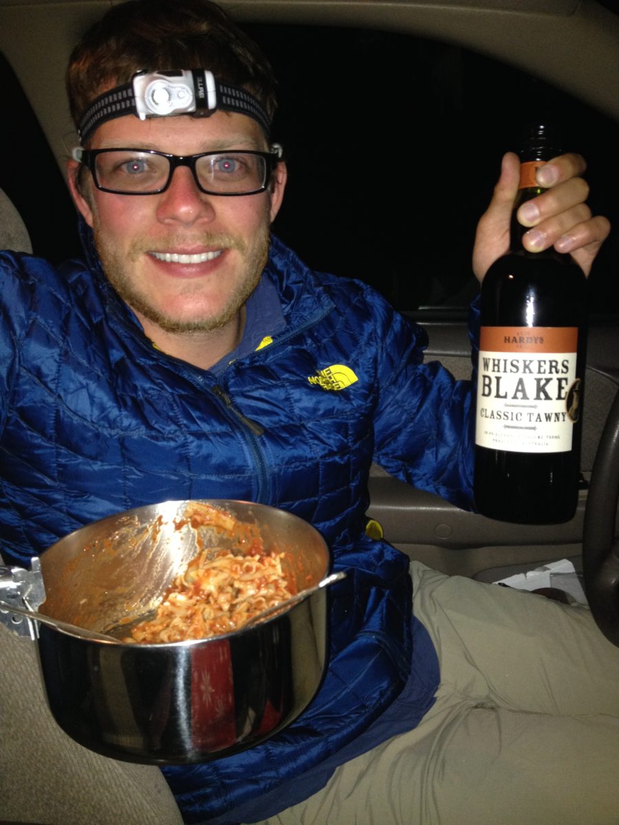 Man hold bottle of Tawny with spaghetti in bowl in other hand.
