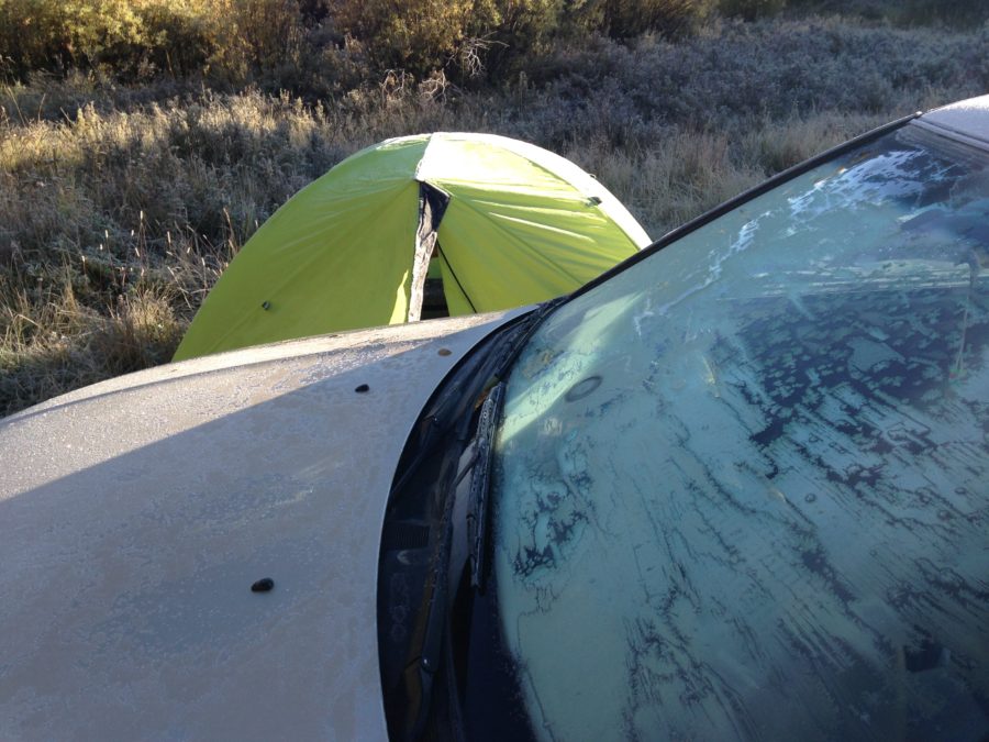 Ice frozen on car windshield and tent on ground.