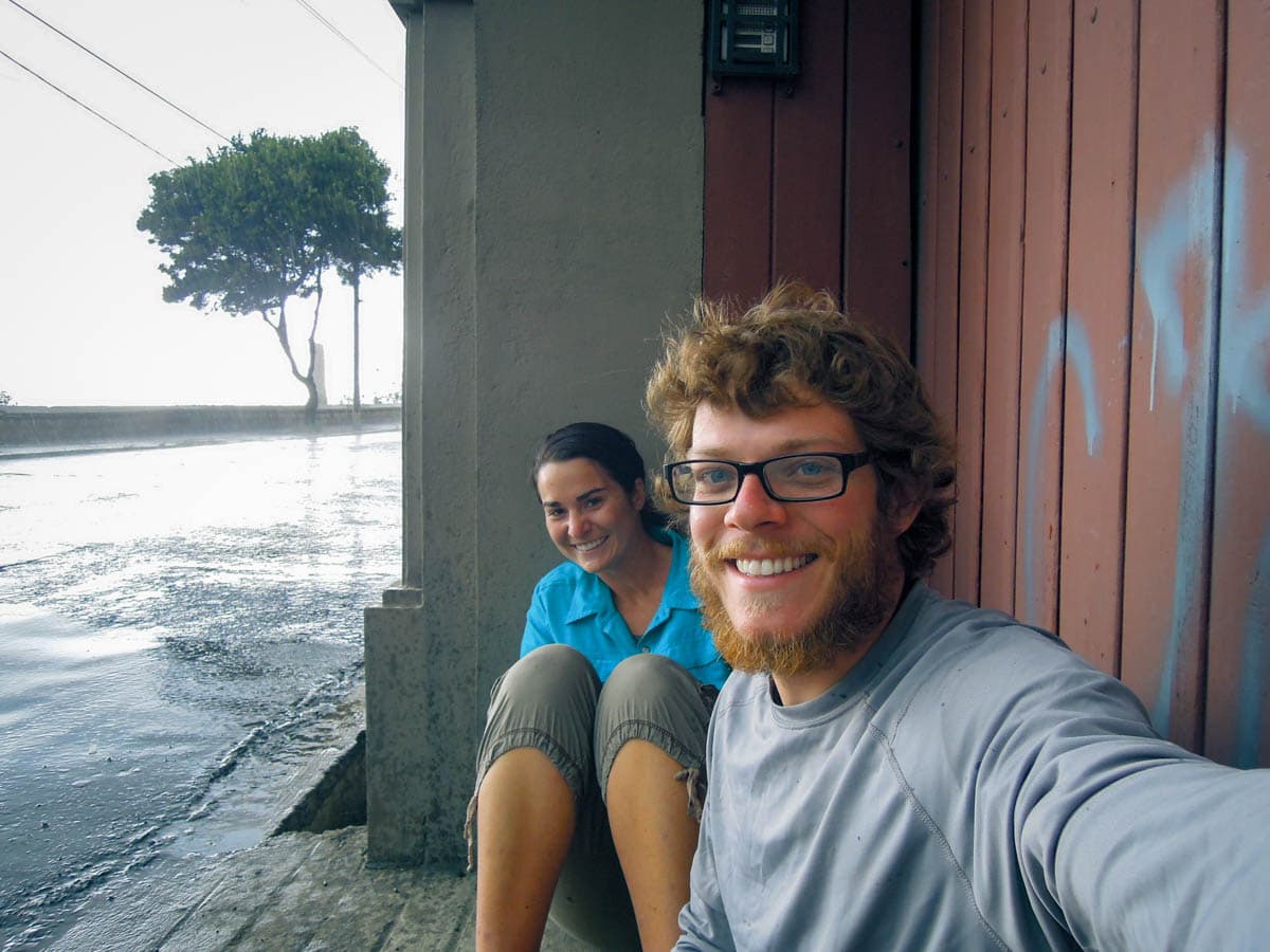 Young couple take selfie in rain under cover.