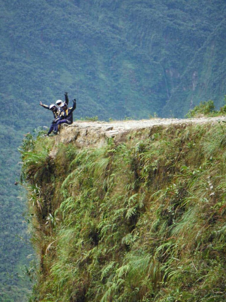 Riders take a photo on cliff road.