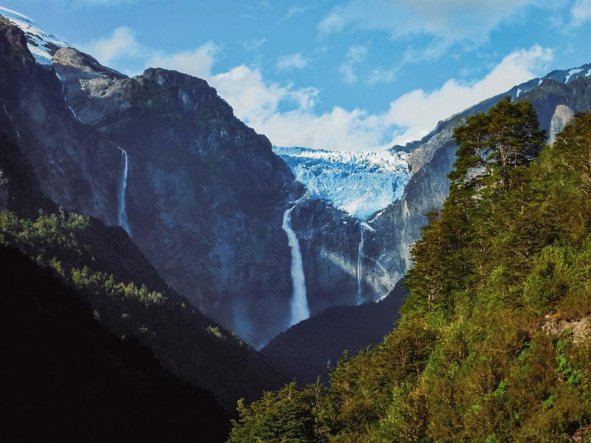 Glacier in mountain cliff with waterfall coming off below it.