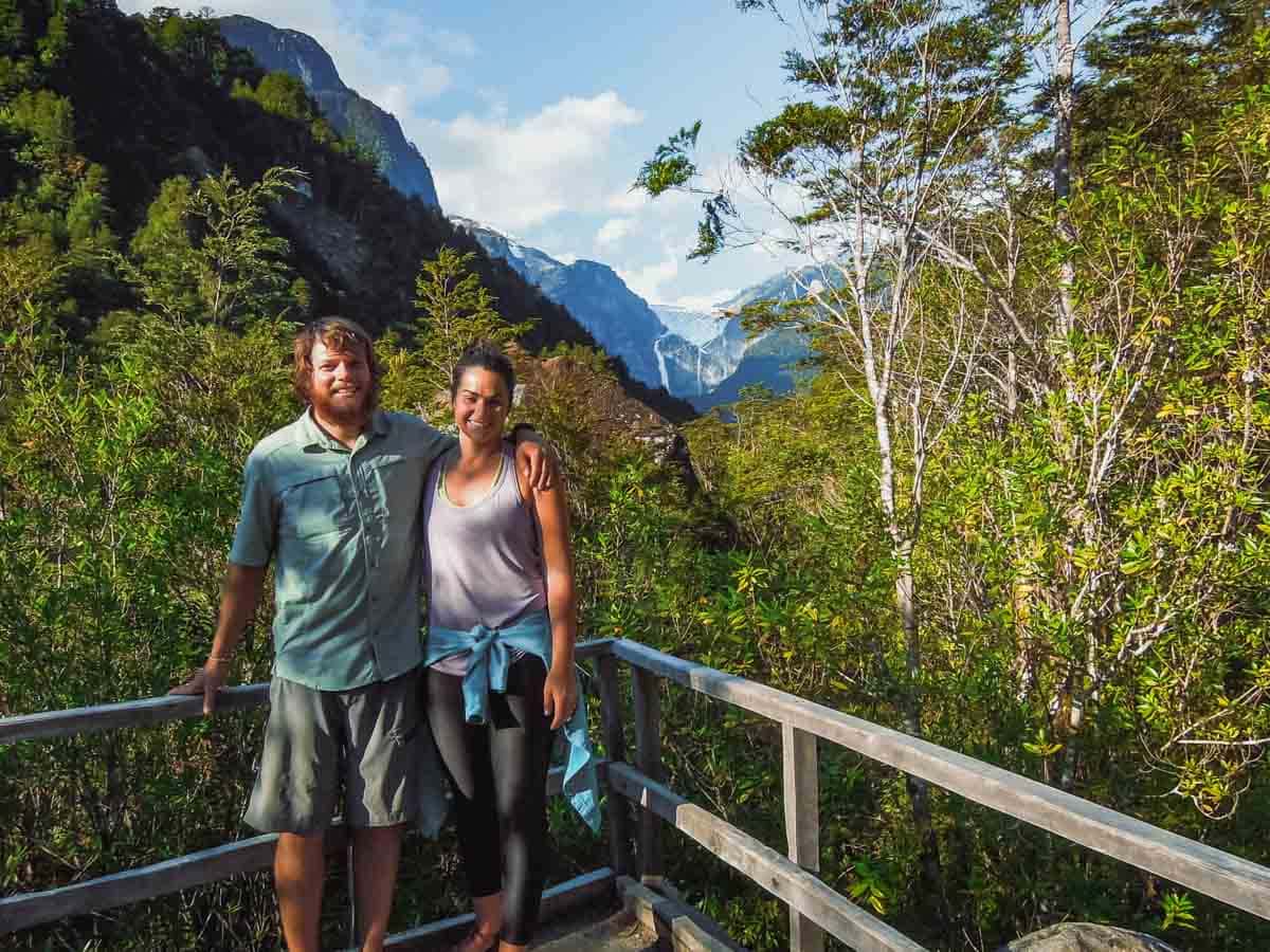Young couple take photo near large glacier.