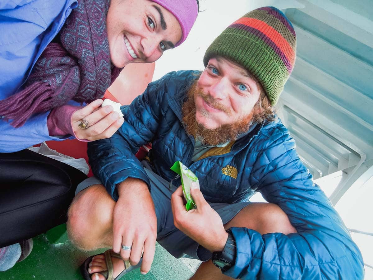 young couple smile and eat food on ferry.
