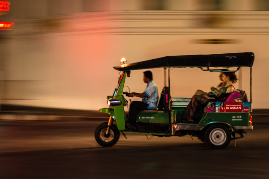 Motion blur in the background of a TulTuk driving in Bangkok, Thailand.