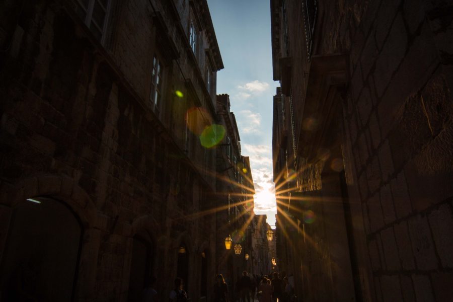 sun star flare through dark buildings in the city