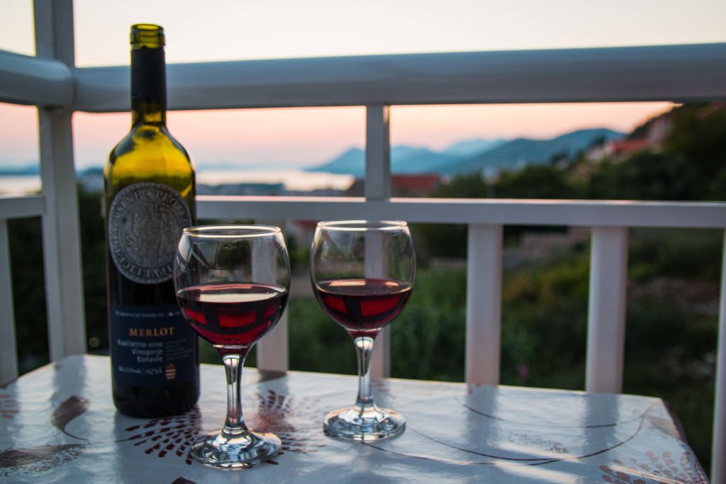 Croatian wine in bottle with two glasses on table overlooking sunset over Adriatic Sea