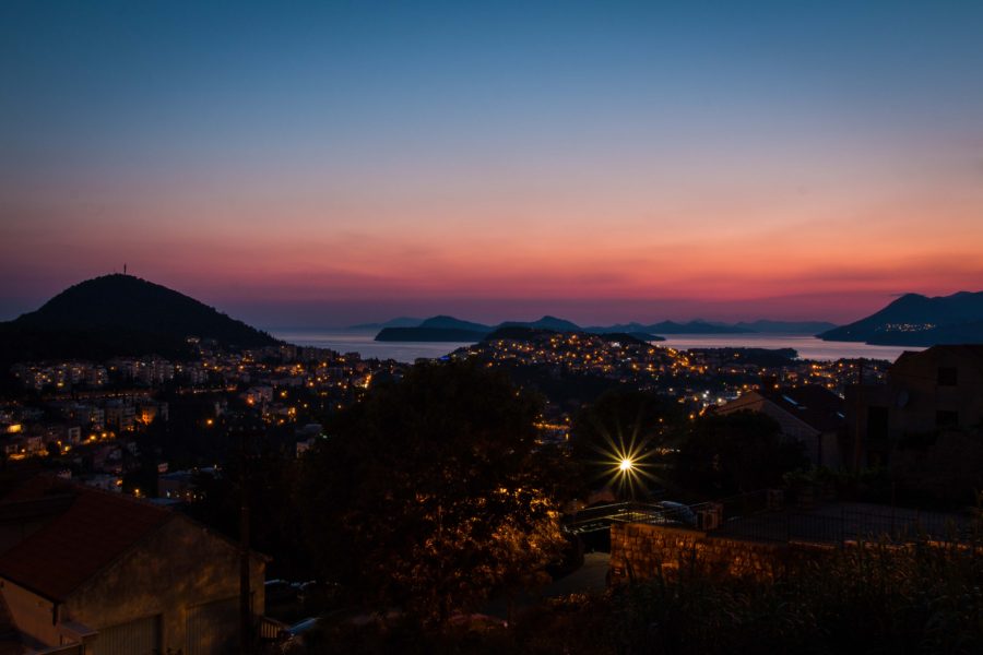 colorful sunset with pinks and purples over the Adriatic sea with islands and lit up city.