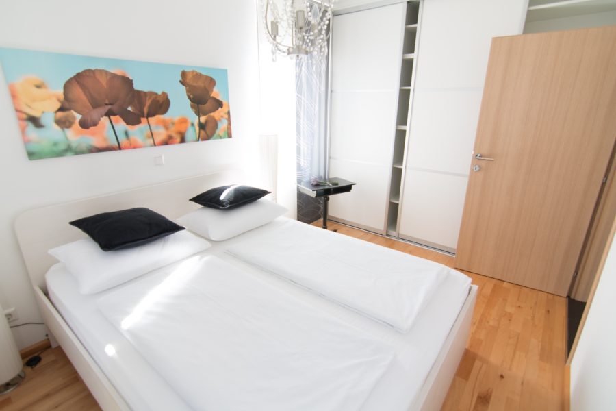 bed with white bedding and colorful artwork on the wall of flowers