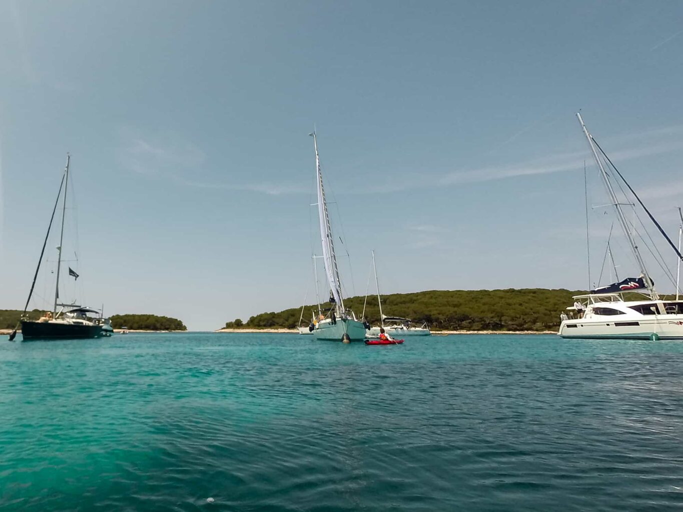 Kayaking in a harbor with sailboats.