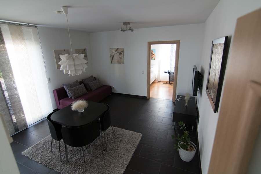 living room and dining area in open floor plan apartment with door open to bedroom in the back