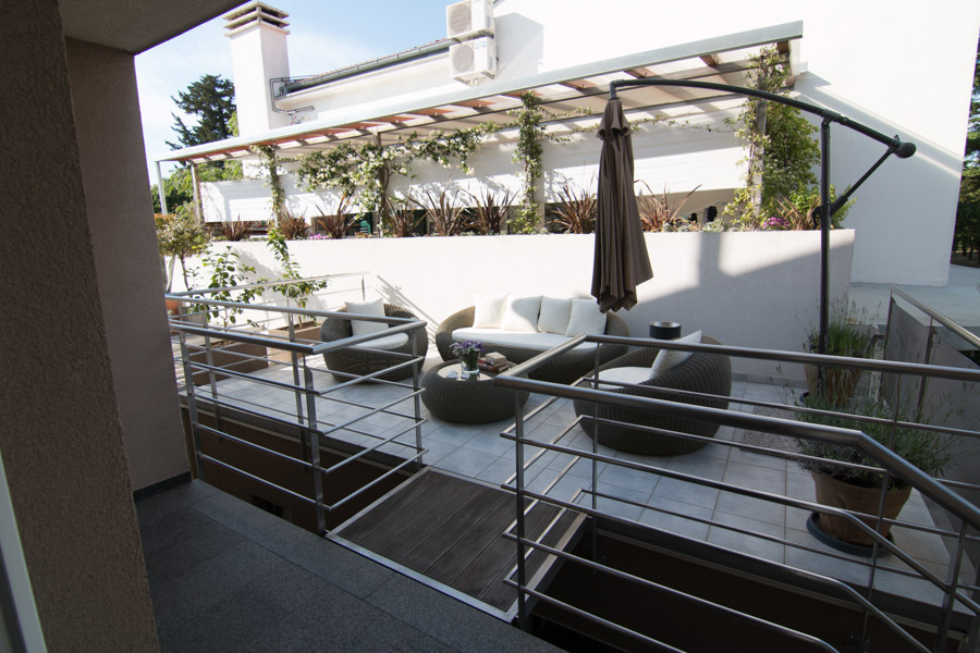 terrace with wicker outdoor couches and table with umbrella unopened on side