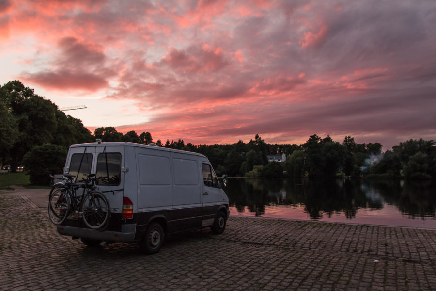 van on water with sunset, pink and purple sunset behind van, campervan in Lubeck, arboursabroad, Germany