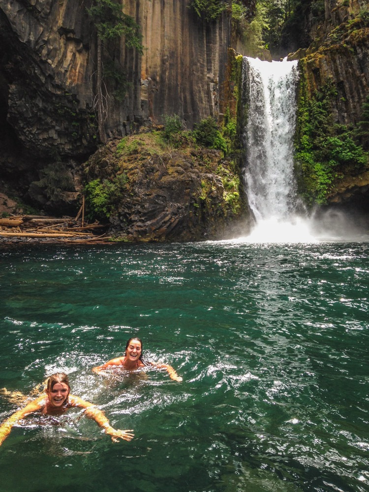 Two girls swimming under Toketee Falls