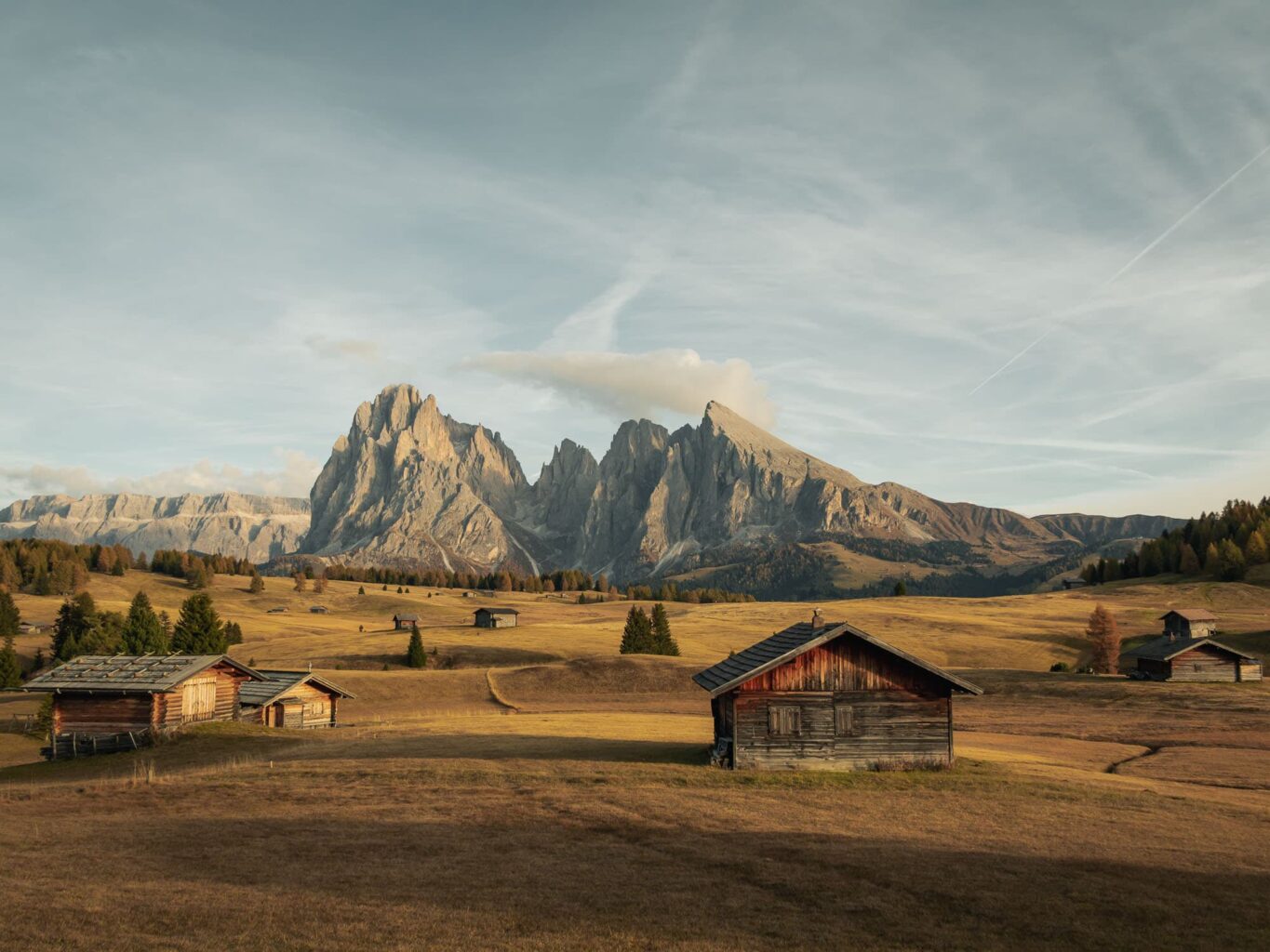 Cabins and buildings in open meadow on top of high dolomite mountains in Italy called Alpi di siusi.