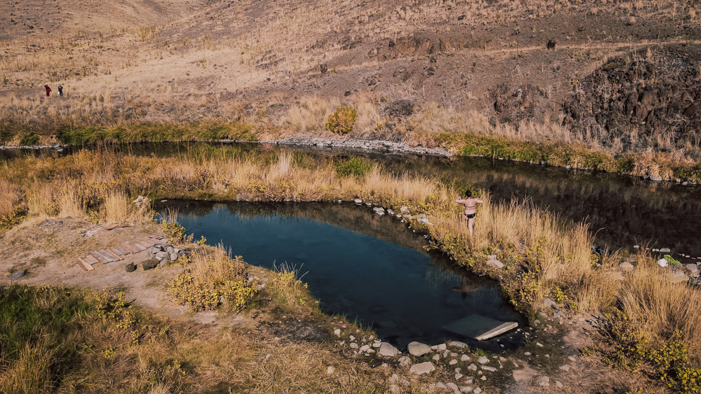 Juntura Hot Springs on the rivers edge with woman walking around the side, ArboursAbroad