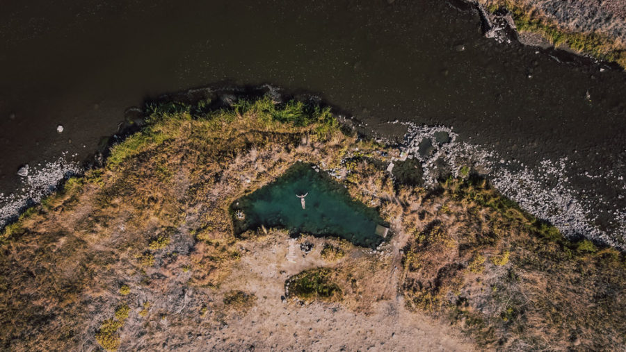 drone shot of woman floating in hot spring on river bend, ArboursAbroad