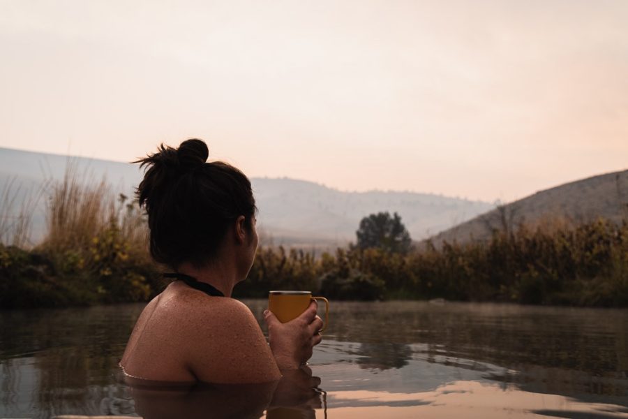 woman in hot spring with coffee mug looking at the sunset, ArboursAbroad