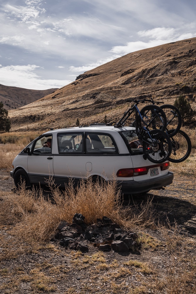 rock fire pit with man driving van behind, Arboursabroad, Vantrails