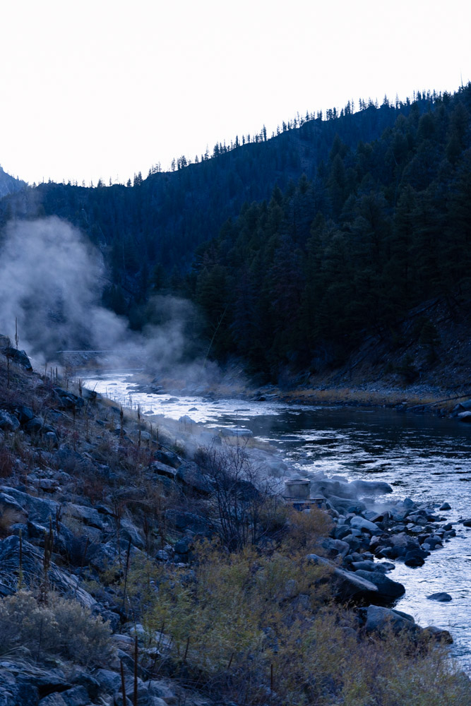 hot springs steaming on the side of a river with mountain in the background, arboursabroad