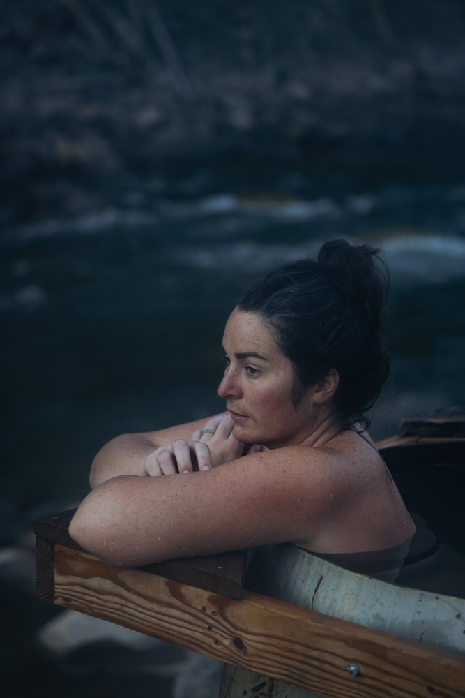 woman relaxing in hot spring kettle with river behind, Idaho, ArboursAbroad