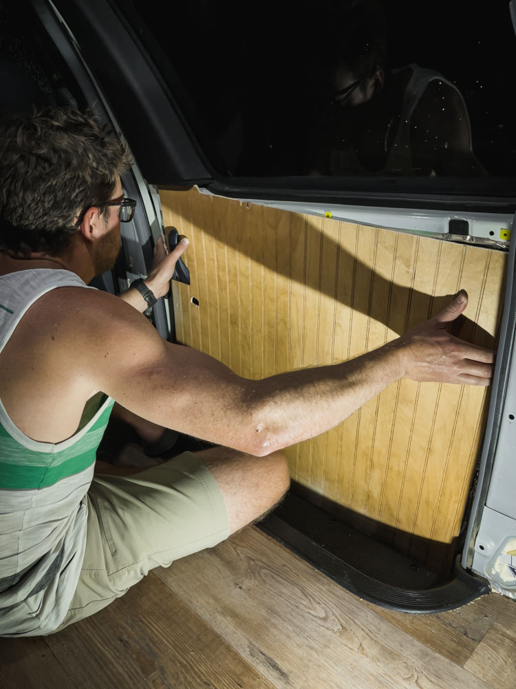 man installing plywood van panel to camper van door, arboursabroad