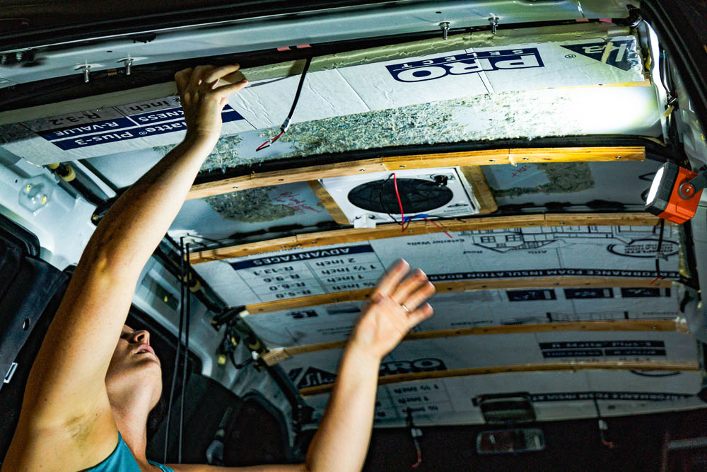 woman installing insulation in campervan ceiling, arboursabroad
