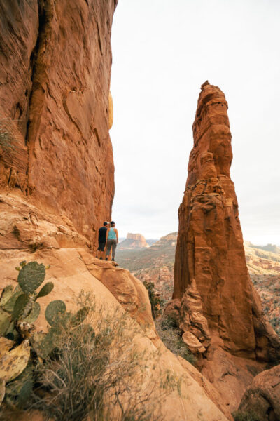 A couple looking out at the red rock views from the second saddle of Cathedral Rock with rock spires in front of them.