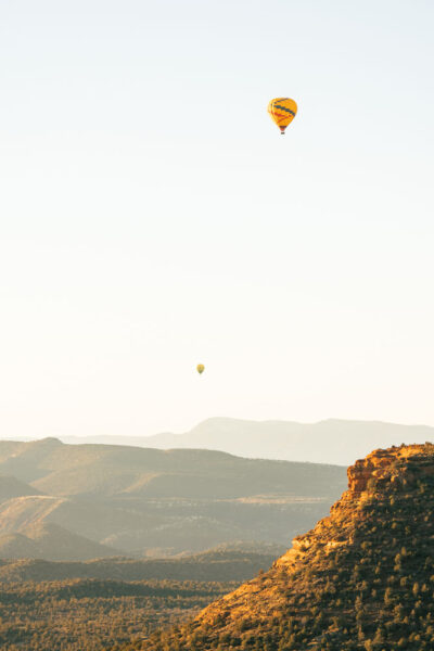 A sunrise hike view from Doe Mountain in Sedona, with two hot air balloons in the sky.