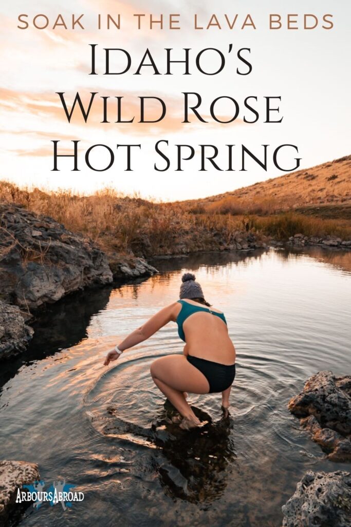Woman getting into a hot spring with a beanie on at sunset with text overlaying the image stating, "soak in the lava beds, Idaho's Wild Rose Hot Spring".