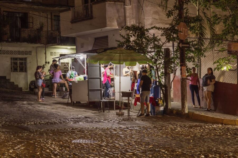 Maria Taqueria taco stand in Puerto Vallarta in the night with people standing around it.