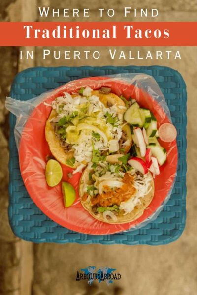 Where to find traditional tacos in Puerto Vallarta in text with two tacos on a plate on a blue stool.