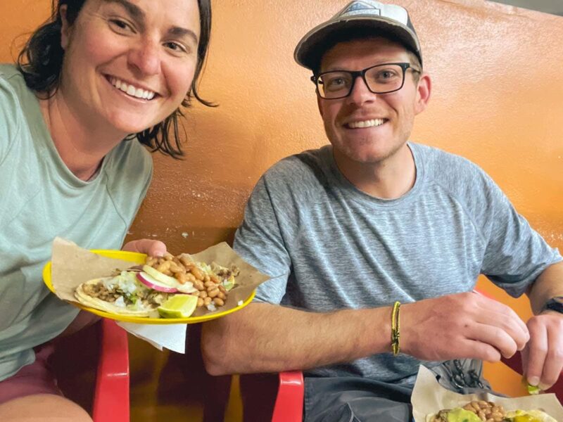 ArboursAbroad sitting in red chairs eating tacos from a taco stand in Puerto Vallarta.