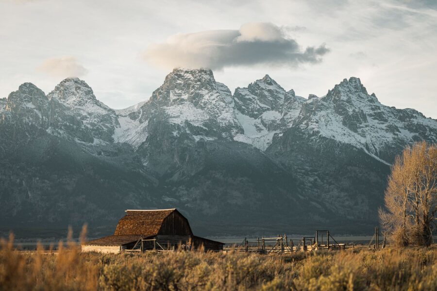 Old barn in prairie with mountains behind.