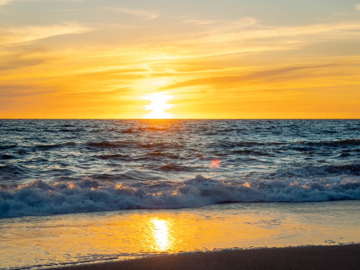 Yellow sunset over the ocean in Puerto Vallarta, reflecting off the water.
