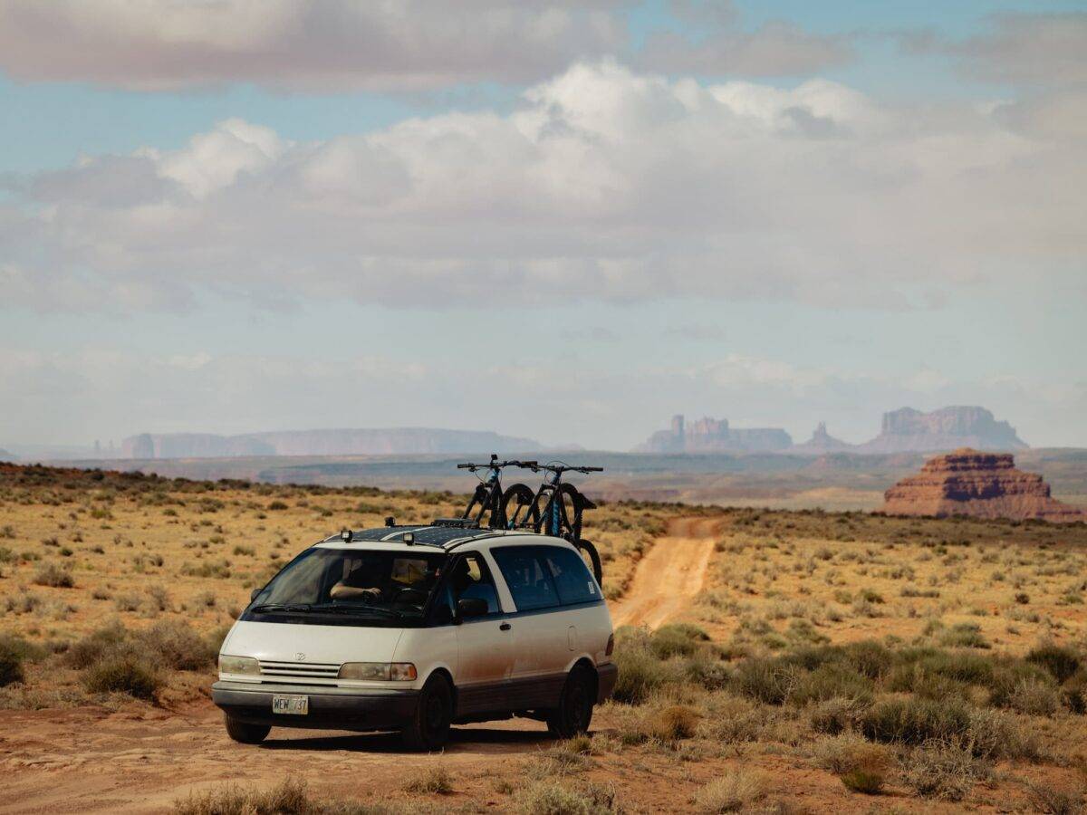 Vantrails van parked on dirt road for free camping with Monument Valley in the background.