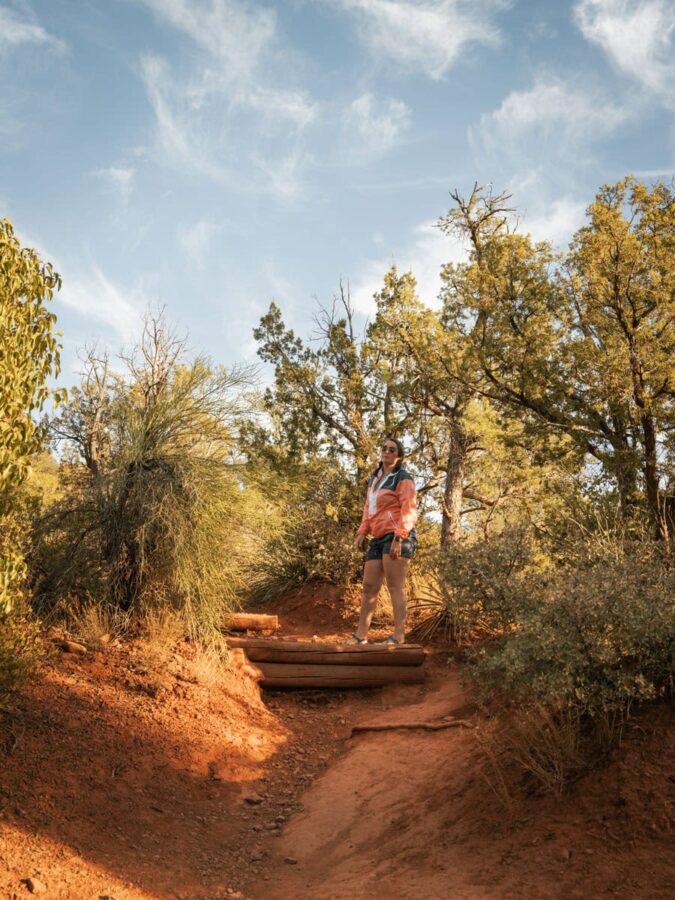 Heather from ArboursAbroad hiking on red Sedona trail with big step built in trail to prevent runoff.