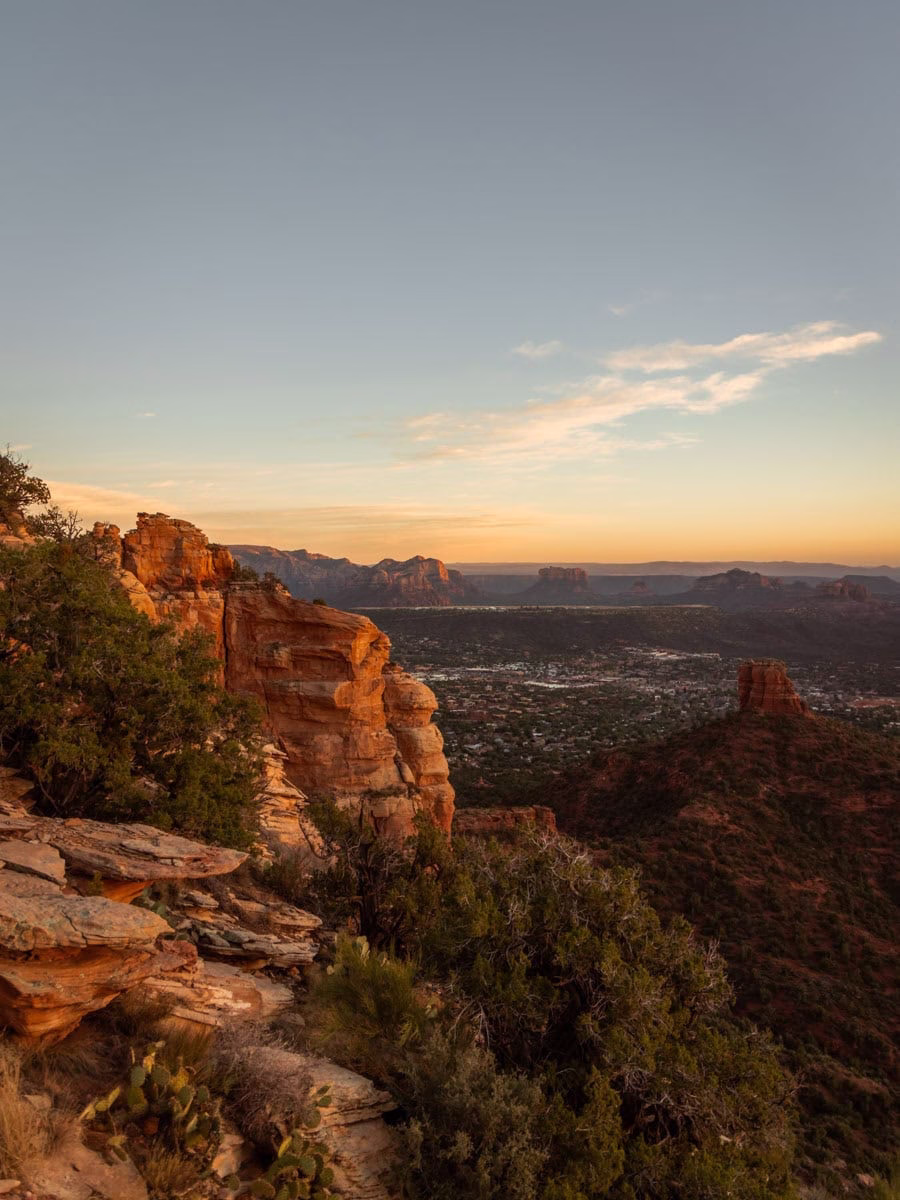 Sunset in Sedona with yellows and oranges on the horizon and lit up rocks in the foreground from Lizard Head.