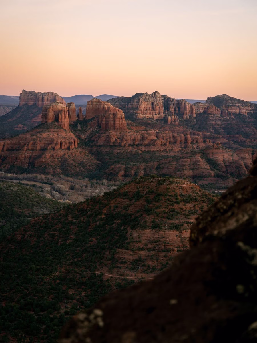 Pastel sunset sky over the red rock formations of Sedona towering out of the ground from the short hike to Schuerman Mountain Vista in West Sedona.