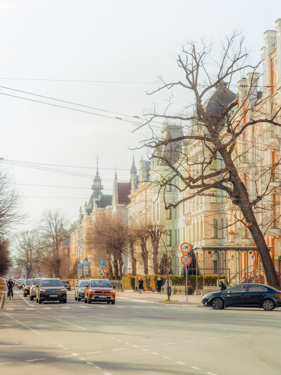 Wide city boulevard with parked cars and historic buildings near Riga's city center