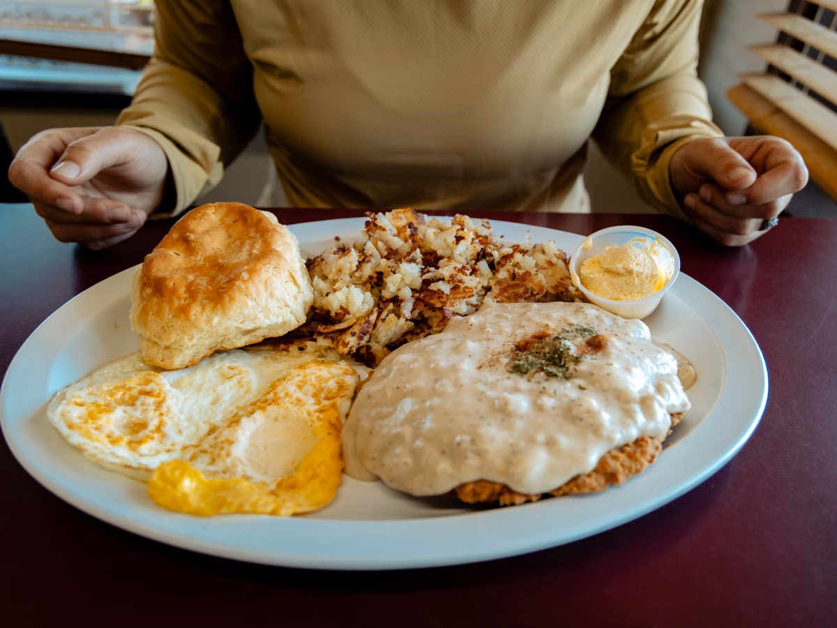 Heather with her diner-style brunch plate with chicken fried steak, gravy, eggs, and hash browns at Cheyenne Cafe in Joseph, Oregon
