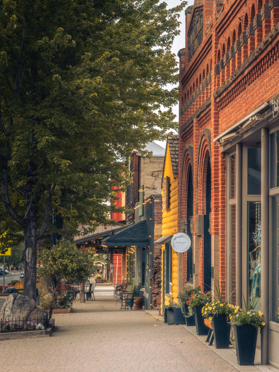 Historic brick storefronts and tree-lined sidewalk in downtown Joseph, Oregon.