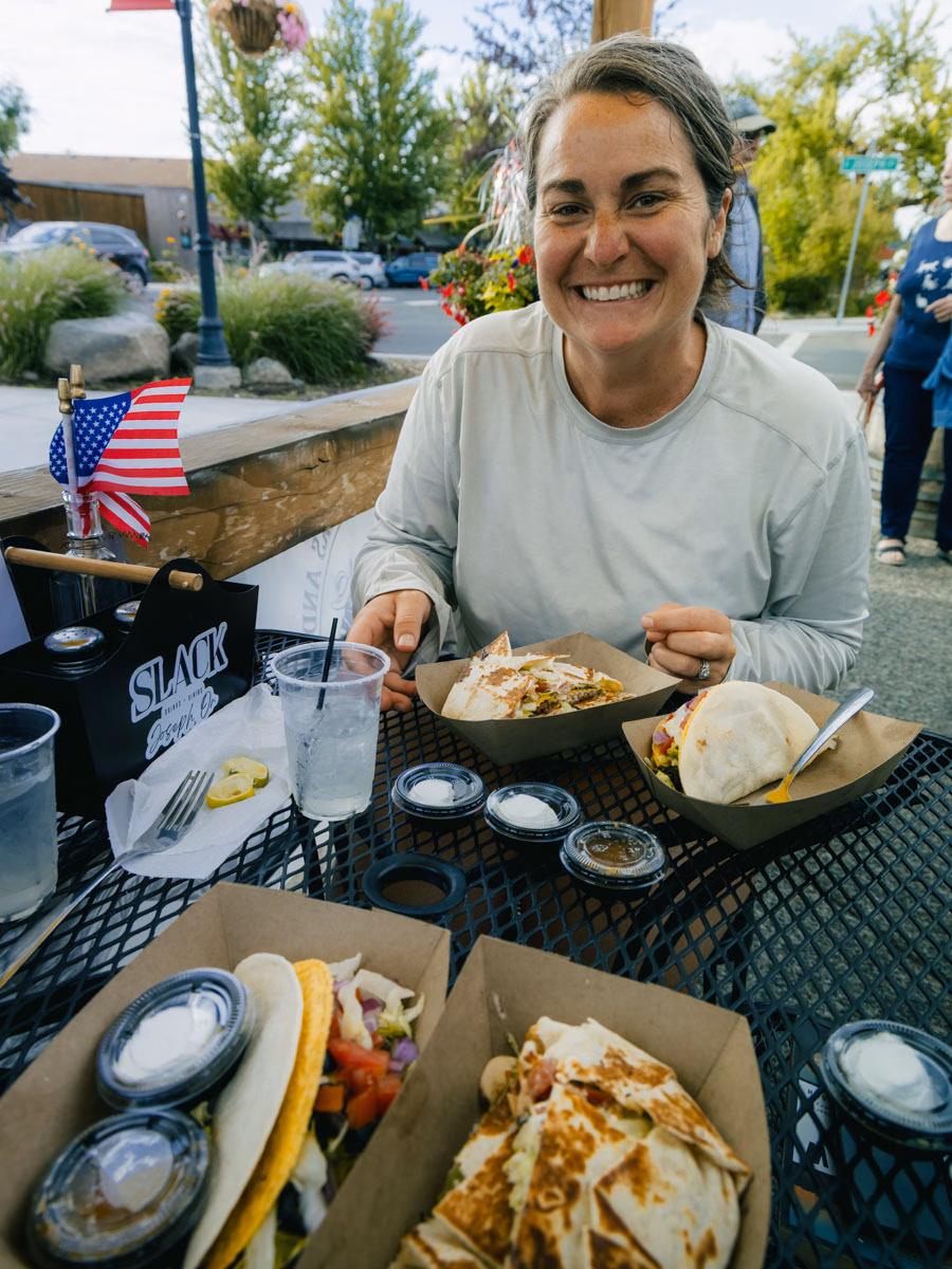 Heather smiling while eating tacos outdoors during Taco Tuesday at Slack in Joseph, Oregon