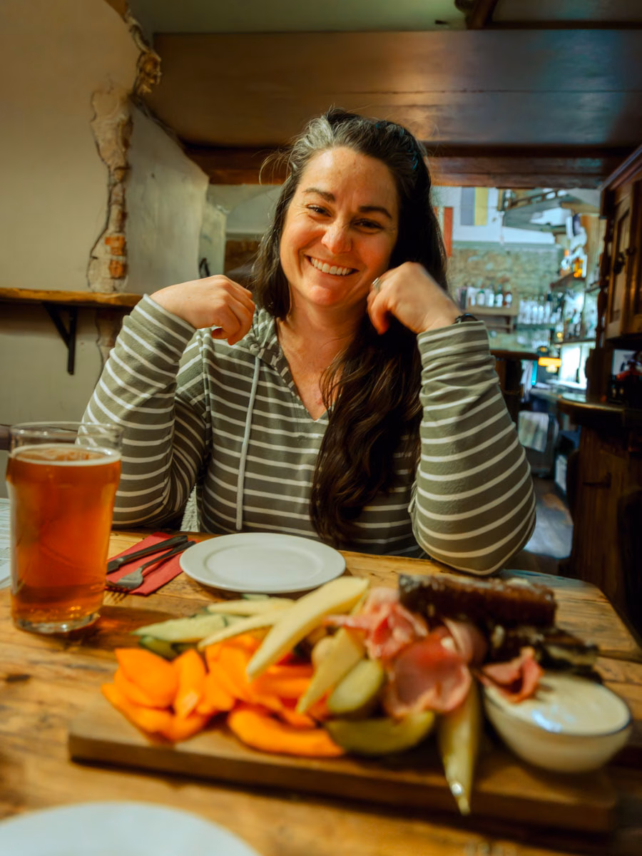 Heather from ArboursAbroad smiling at a table with the beer board at Ala, a restaurant that's an absolute must when visiting Riga!